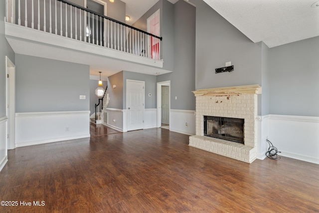 unfurnished living room with dark hardwood / wood-style floors, a fireplace, and high vaulted ceiling