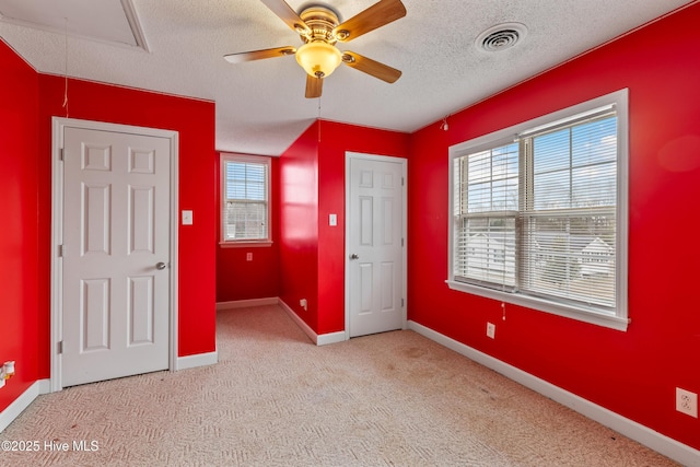 unfurnished bedroom with light carpet, a textured ceiling, and ceiling fan