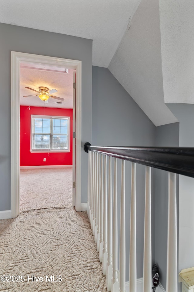 hallway with vaulted ceiling, carpet floors, and a textured ceiling