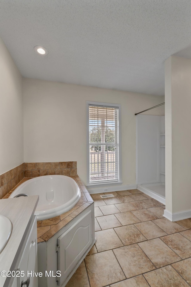 bathroom with tile patterned floors, a tub to relax in, a textured ceiling, and vanity