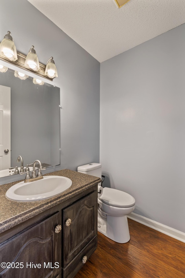 bathroom with wood-type flooring, toilet, a textured ceiling, and vanity