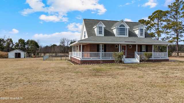 farmhouse featuring a front yard, covered porch, and a shed