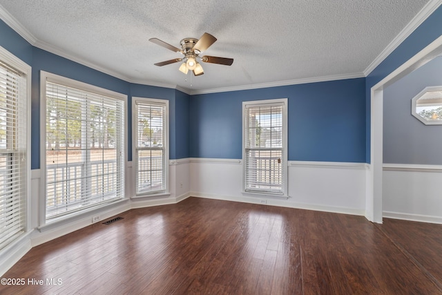 empty room with dark wood-type flooring, ceiling fan, plenty of natural light, and crown molding