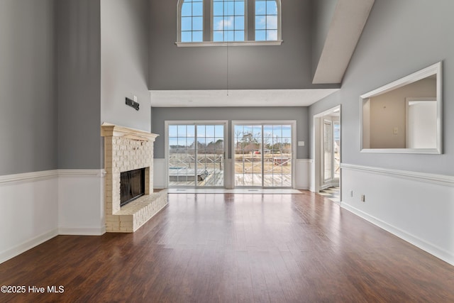 unfurnished living room featuring dark hardwood / wood-style floors, a towering ceiling, and a fireplace