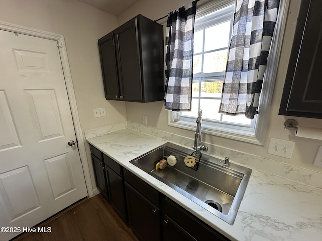 kitchen featuring light stone counters, dark wood-type flooring, and sink