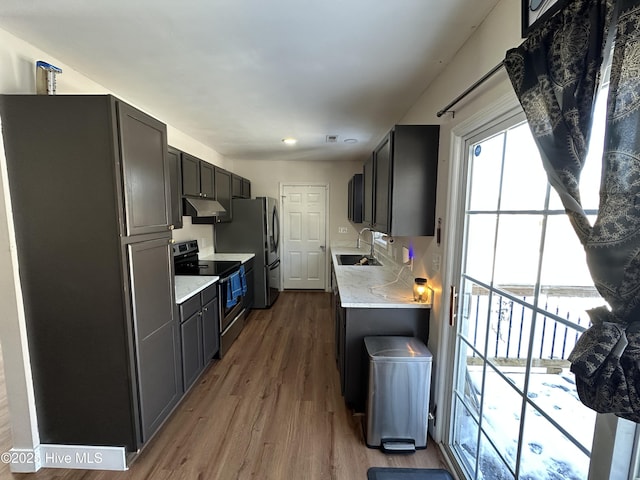 kitchen featuring stainless steel range with electric stovetop, sink, hardwood / wood-style flooring, and light stone countertops