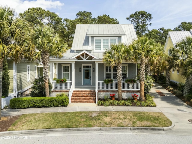 view of front facade with covered porch, metal roof, and driveway