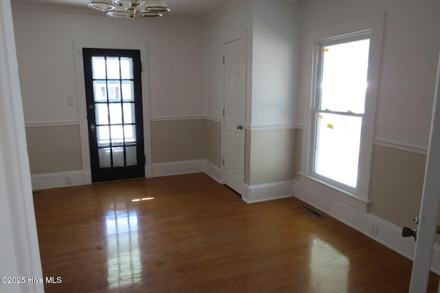 interior space featuring baseboards, visible vents, ornamental molding, wood finished floors, and an inviting chandelier