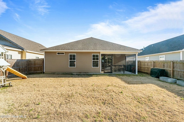 back of property featuring a sunroom and a lawn