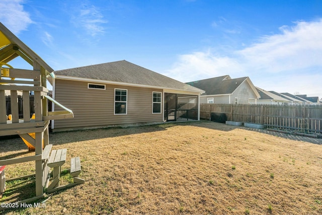 back of property with a lawn and a sunroom