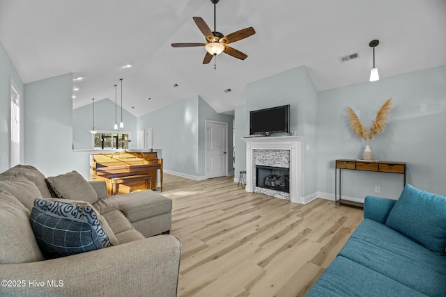 living room featuring a fireplace, light hardwood / wood-style floors, ceiling fan, and lofted ceiling