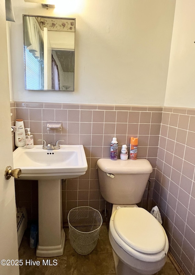 bathroom featuring toilet, sink, and tile walls