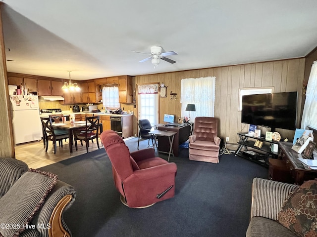 living room with wine cooler, ceiling fan with notable chandelier, and wood walls