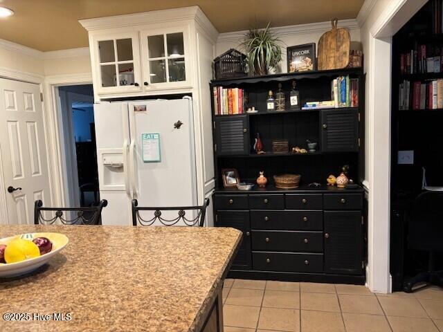 kitchen featuring light tile patterned flooring, white refrigerator with ice dispenser, ornamental molding, and white cabinets