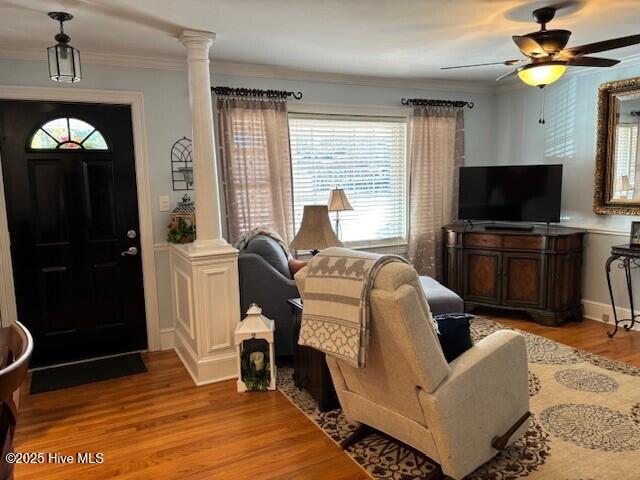 living room with decorative columns, ornamental molding, and light hardwood / wood-style floors