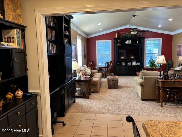 carpeted living room with ceiling fan, ornamental molding, and vaulted ceiling