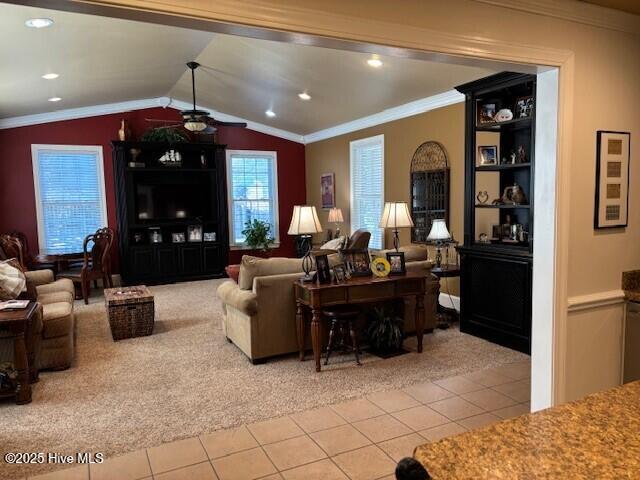 tiled living room featuring vaulted ceiling, ornamental molding, and ceiling fan