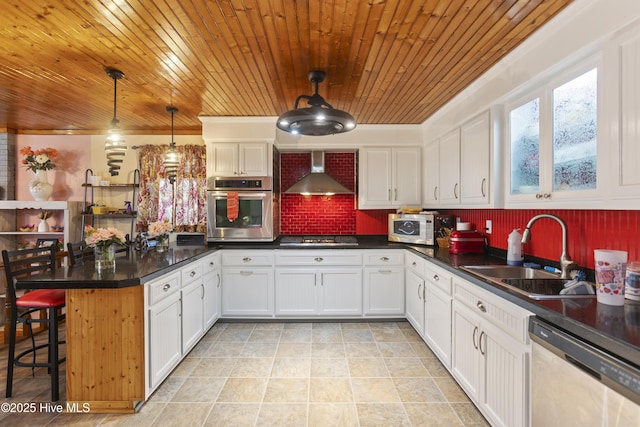 kitchen featuring appliances with stainless steel finishes, hanging light fixtures, white cabinets, sink, and wall chimney exhaust hood