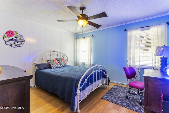 bedroom with crown molding, hardwood / wood-style floors, a textured ceiling, and ceiling fan