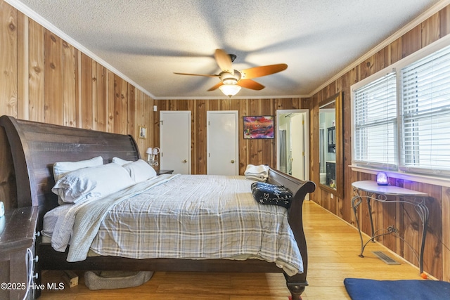 bedroom featuring ceiling fan, ornamental molding, and wooden walls