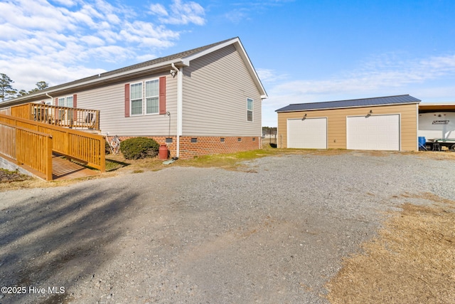 view of side of home featuring an outbuilding, a garage, and a deck