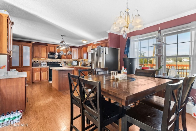 dining space with crown molding, a textured ceiling, a chandelier, and light hardwood / wood-style flooring