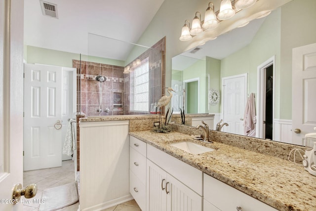 bathroom featuring a tile shower, vanity, tile patterned flooring, and lofted ceiling