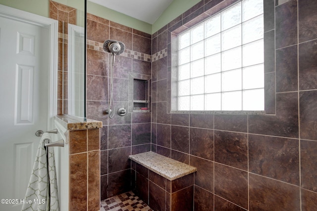 bathroom with vaulted ceiling and tiled shower