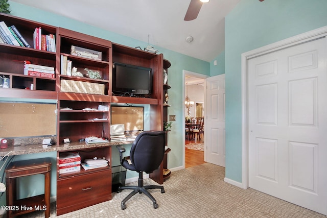 carpeted office featuring lofted ceiling and ceiling fan with notable chandelier