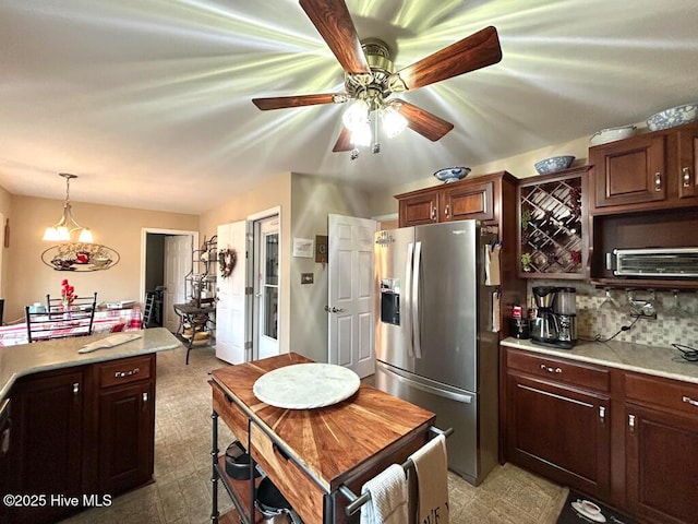 kitchen featuring decorative light fixtures, decorative backsplash, ceiling fan, stainless steel fridge with ice dispenser, and dark brown cabinets