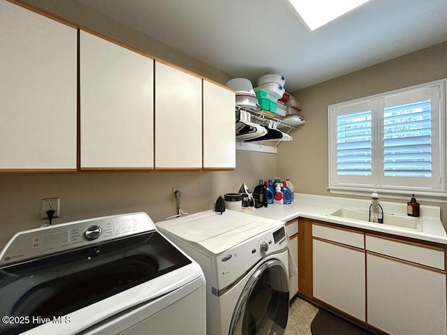 clothes washing area with cabinets, washer and dryer, and sink