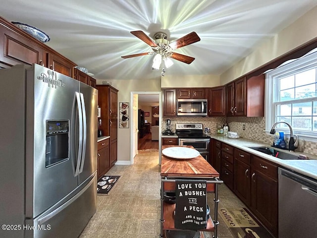 kitchen featuring a kitchen island, tasteful backsplash, sink, ceiling fan, and stainless steel appliances