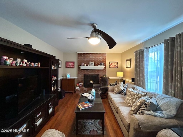 living room featuring a brick fireplace, dark hardwood / wood-style floors, and ceiling fan