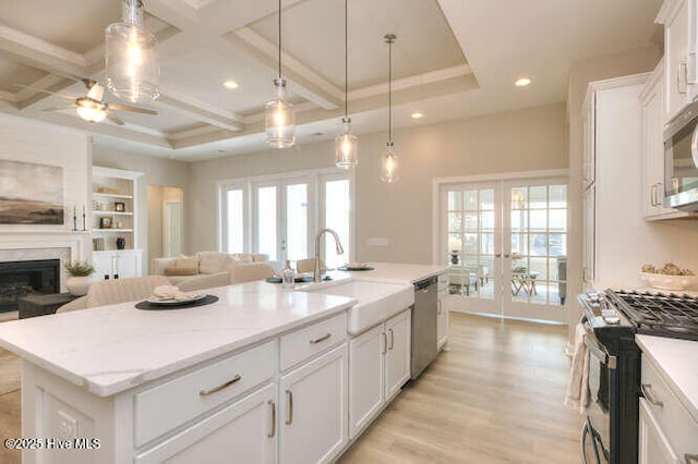 kitchen with appliances with stainless steel finishes, white cabinetry, an island with sink, sink, and french doors