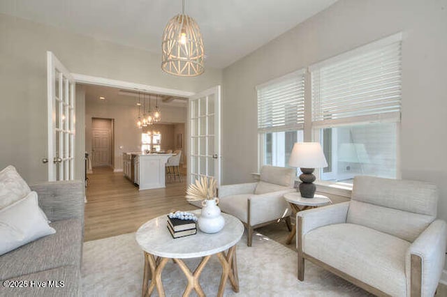 living room with light hardwood / wood-style floors, french doors, and a chandelier