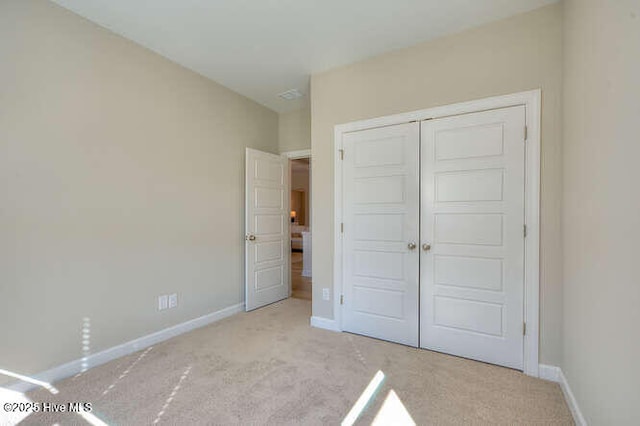 unfurnished bedroom featuring light colored carpet and a closet