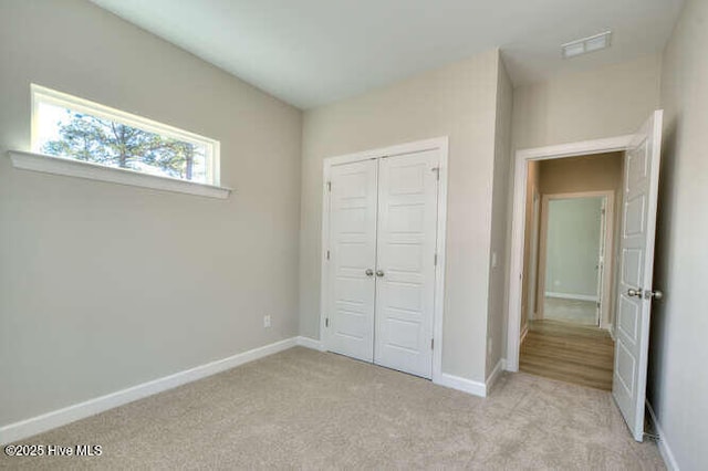 unfurnished bedroom with light colored carpet and a closet