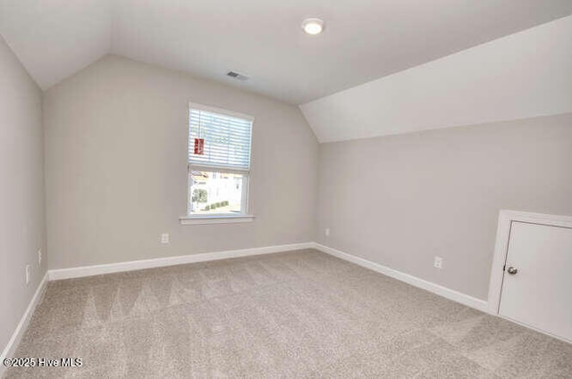 bonus room with vaulted ceiling and light colored carpet