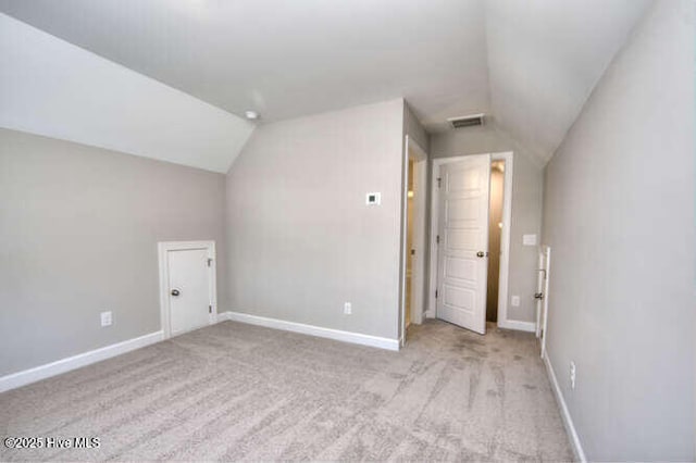 bonus room with light colored carpet and vaulted ceiling