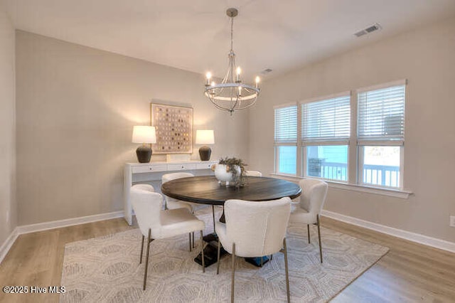 dining space featuring light hardwood / wood-style floors and a chandelier