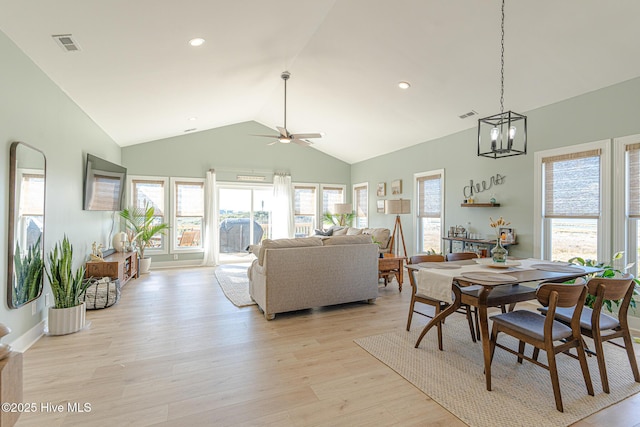 dining room with ceiling fan with notable chandelier, vaulted ceiling, and light wood-type flooring