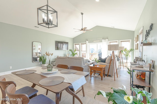 dining space featuring vaulted ceiling, ceiling fan with notable chandelier, and light wood-type flooring