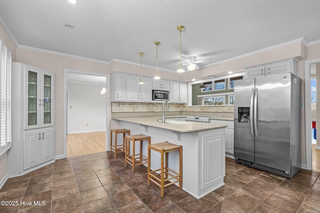 kitchen with pendant lighting, a breakfast bar area, stainless steel appliances, white cabinets, and decorative backsplash