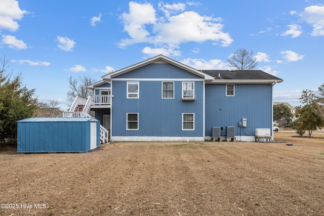 rear view of property with a storage shed, an outdoor structure, cooling unit, and stairs