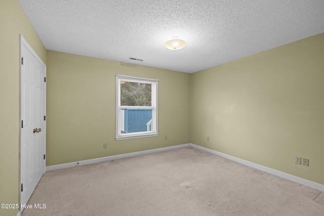 unfurnished room with light colored carpet and a textured ceiling