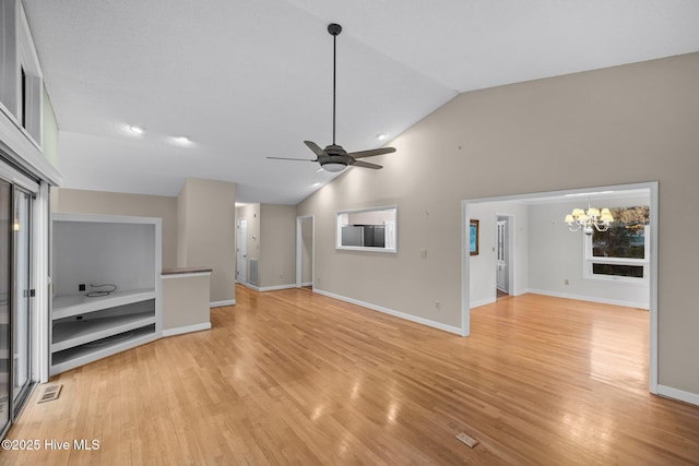 unfurnished living room featuring lofted ceiling, ceiling fan with notable chandelier, and light wood-type flooring