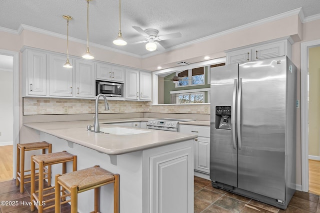 kitchen featuring a kitchen bar, sink, white cabinetry, hanging light fixtures, and appliances with stainless steel finishes