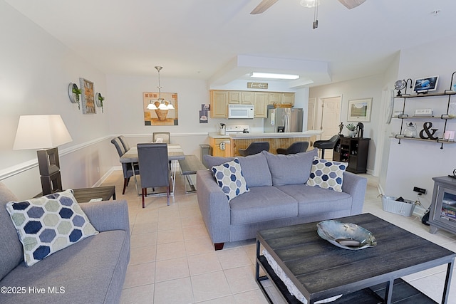 tiled living room with a wood stove and ceiling fan with notable chandelier