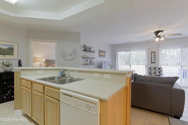 kitchen with sink, light tile patterned floors, a tray ceiling, dishwasher, and a kitchen island with sink