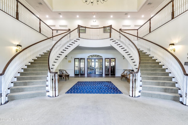 carpeted foyer entrance with a towering ceiling and ornamental molding